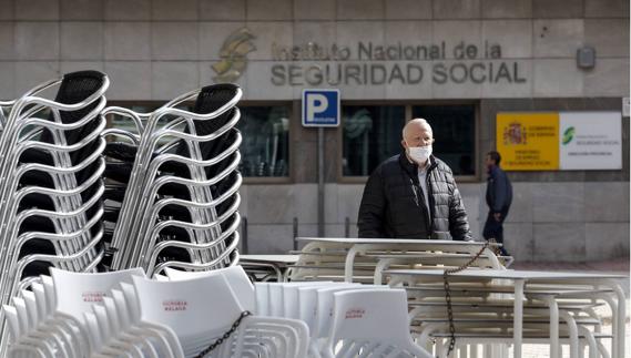 A closed bar's tables and chairs piled up outside a Social Security office in Malaga.