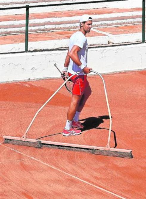 Novak Djokovic, in an unusual image for a player of his level, brushing the clay surface.