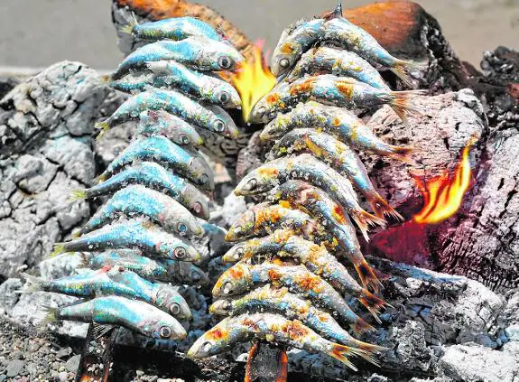 Freshly caught sardines being roasted over charcoal.