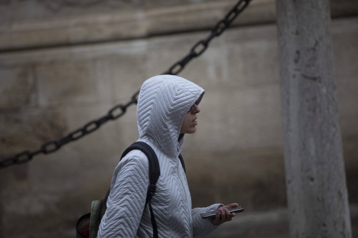 Una mujer pasea con la capucha para protegerse de la lluvia