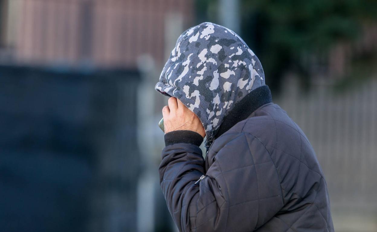 Un hombre con capucha y chaqueta toma un café caliente