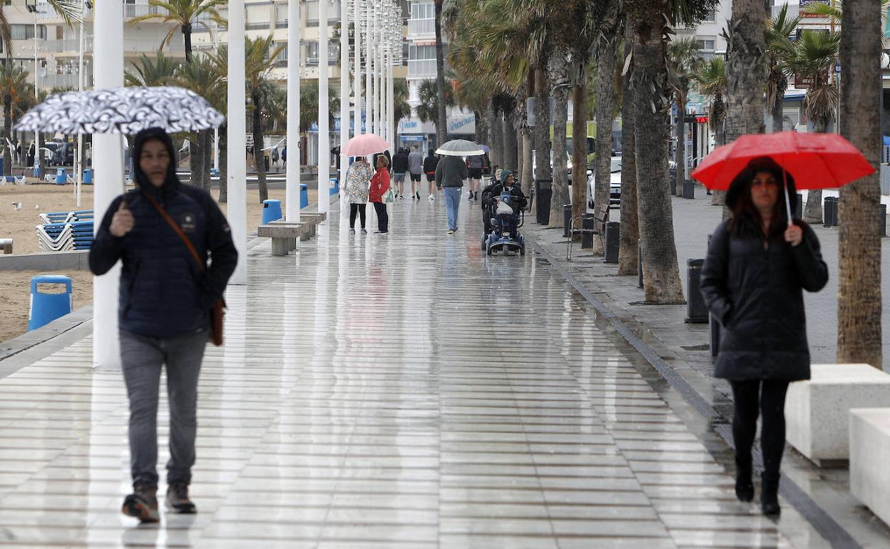 Los transeúntes se protegen de la lluvia en el paseo marítimo de Benidorm 
