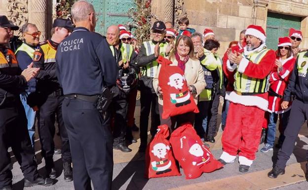 Julia Llopis junto a sacos de regalos recogidos durante la 'Moto Papanoelada' y varios participantes. 