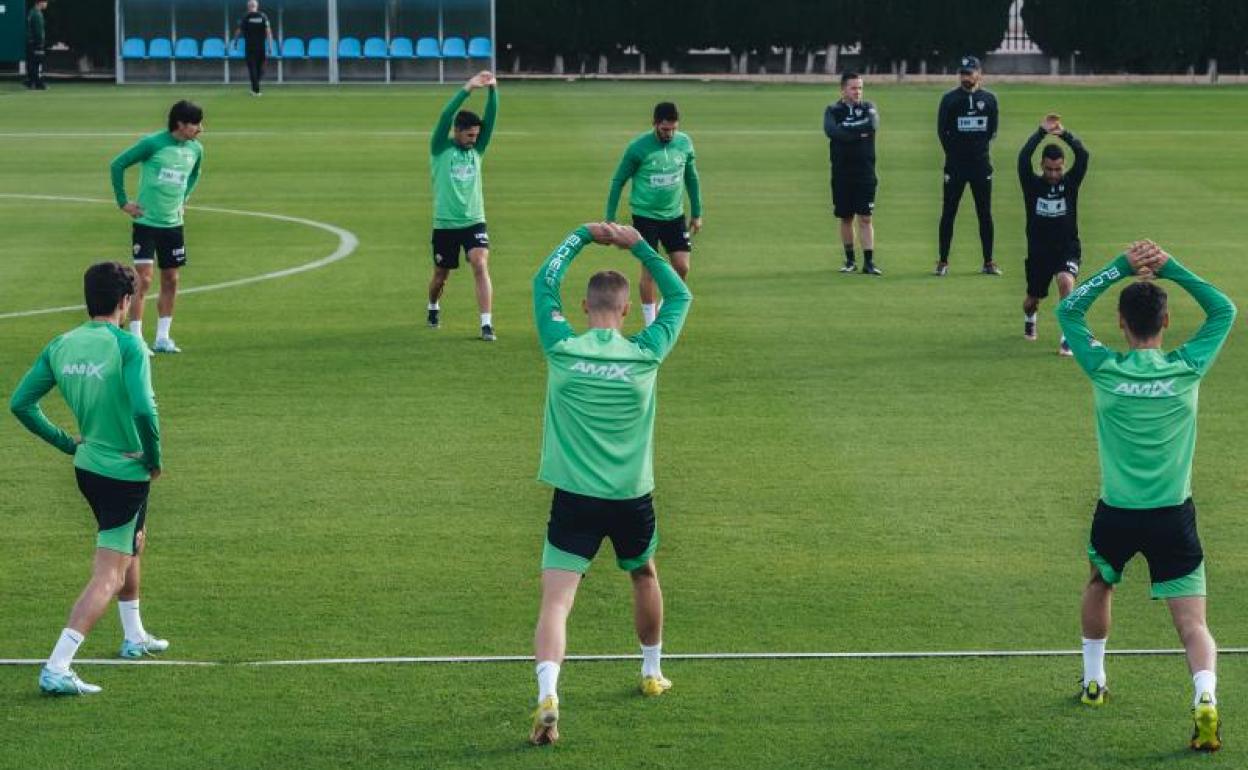 Los jugadores del Elche estiran bajo la mirada de Pablo Machín 