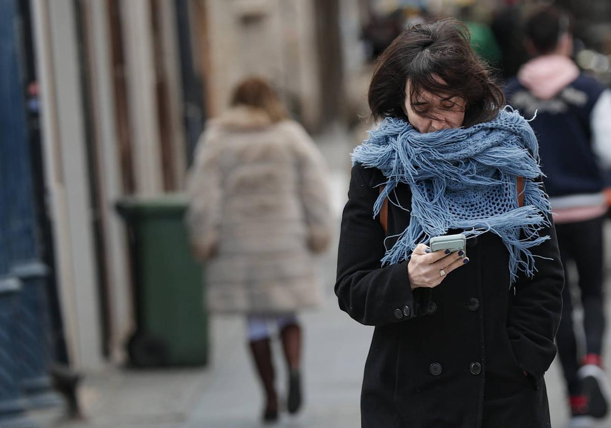 Una mujer camina protegiéndose del frío