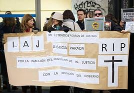 Varios letrados se concentran con una pancarta mientras tiene lugar una reunión del comité de huelga de los letrados con Justicia