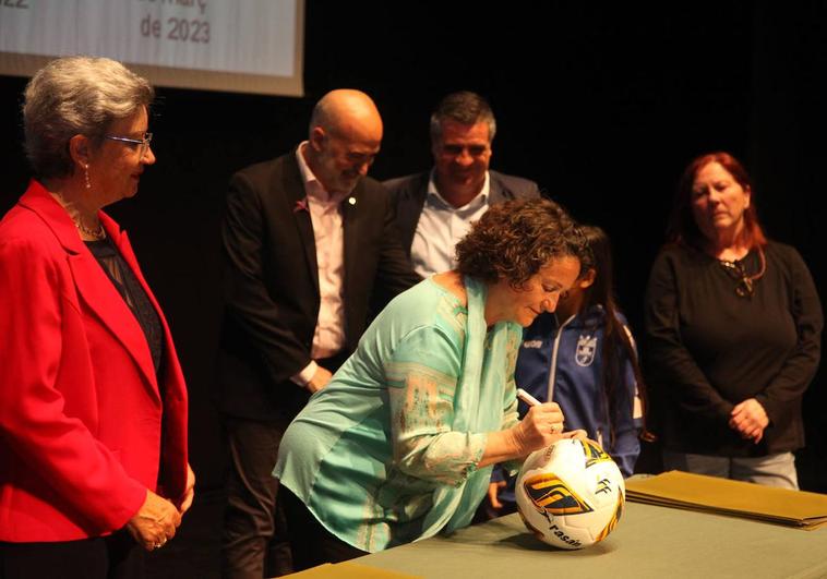 Una de las jugadores firmando el balón de la escuela municipal de fútbol.