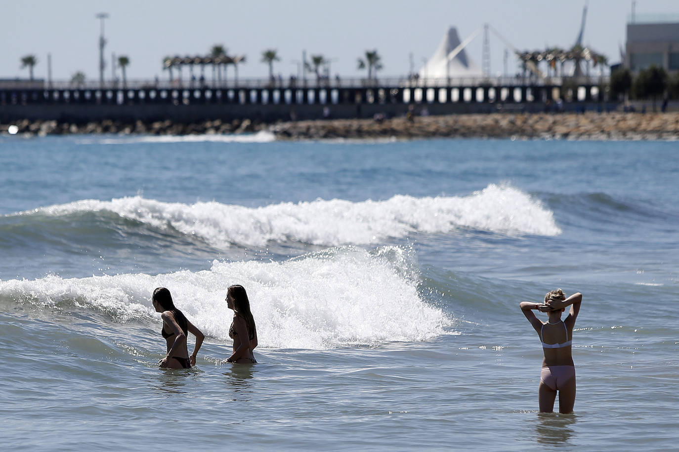 Tres personas se bañan en aguas de la playa del Postiguet en Alicante,