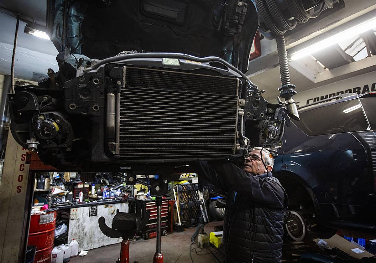Un mecánico trabaja en su taller reparando un coche