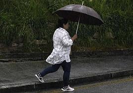 Una mujer se protege de la lluvia con un paraguas.