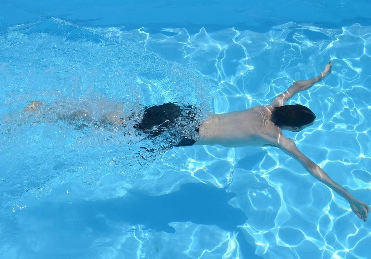 Un joven nadando en una piscina.