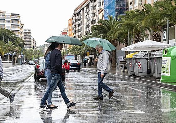 Varias personas cruzan una calle del centro de Alicante bajo la lluvia