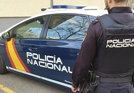 Agente de Policía Nacional con un coche patrulla.
