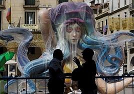 Dos personas delante de una de las piezas de la Hoguera Oficial.