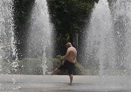 Un hombre se refresca en una fuente pública de Alicante.