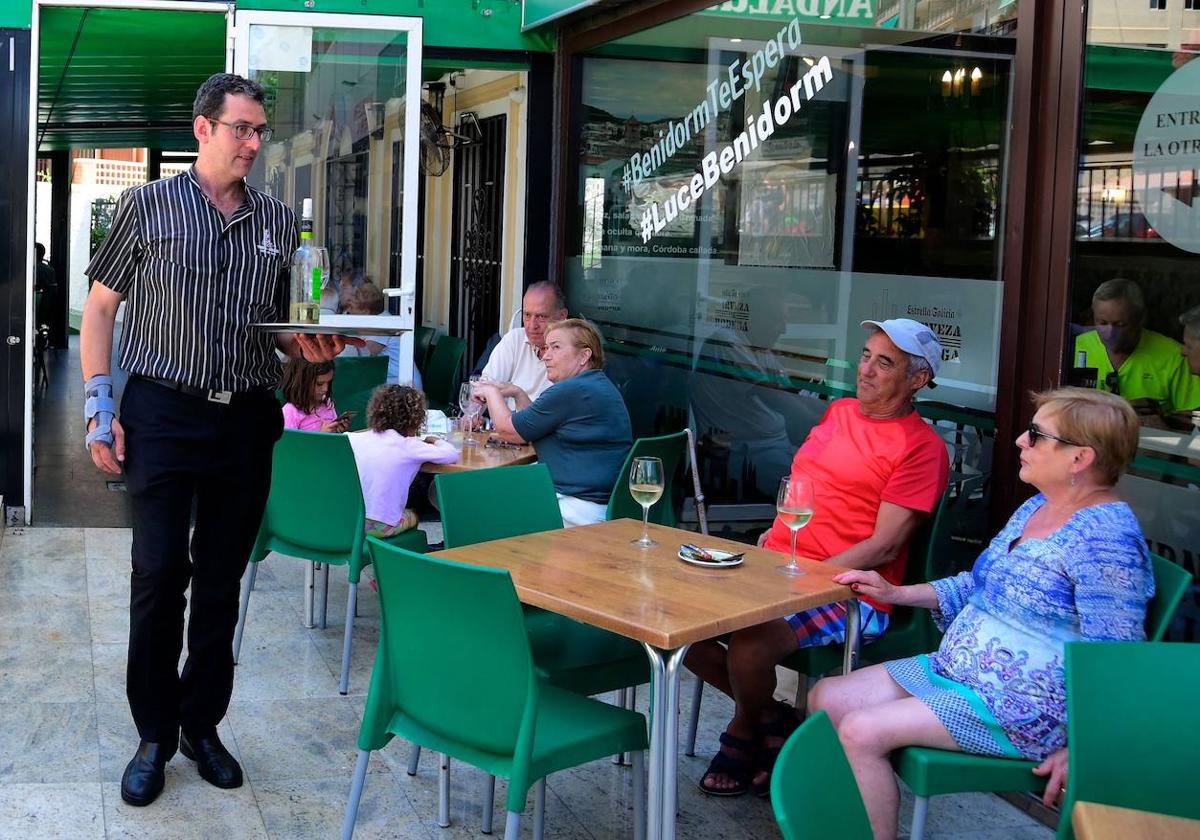 Un camarero sirve a unos turistas en Benidorm.
