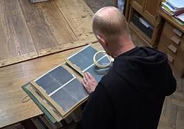 Un monje de la Abadía de Solesmes revisa los manuscritos que transcribirá la IA.