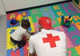 Un miembro de Cruz Roja juega con un niño rescatado.