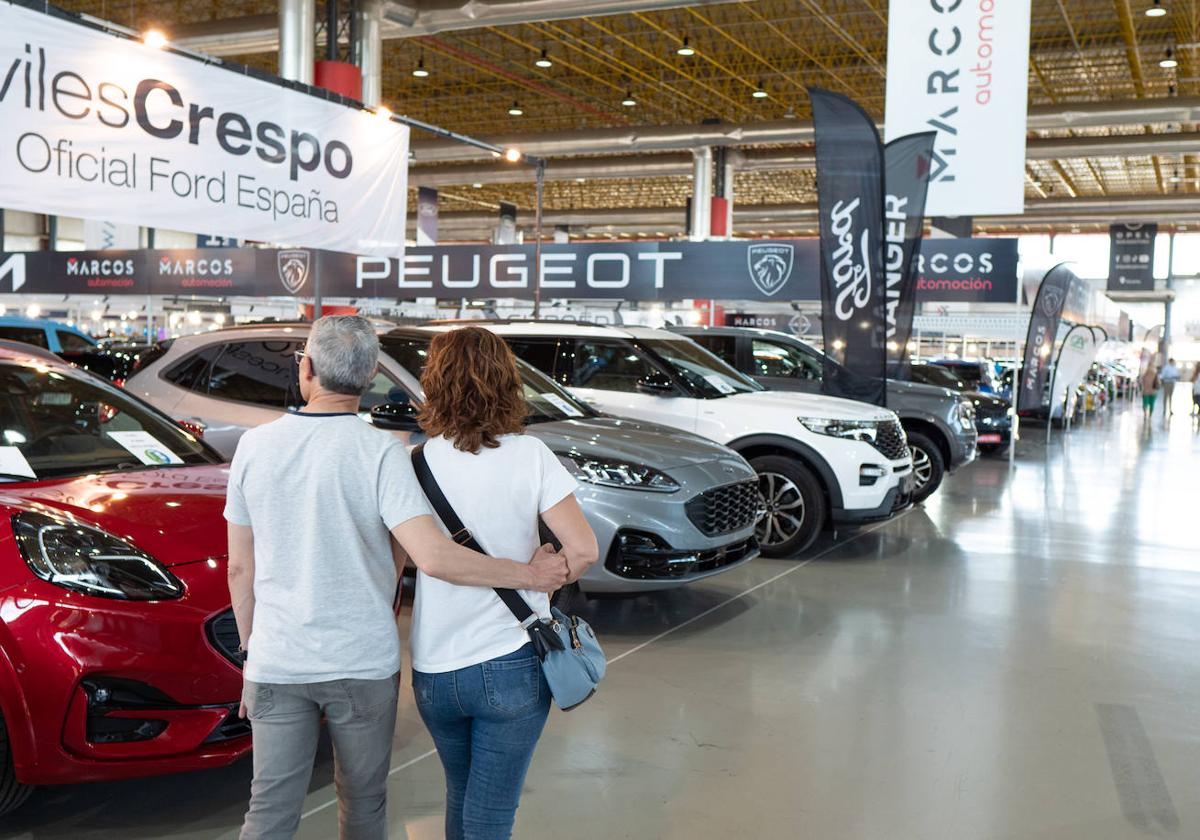 Una pareja busca coche en una feria del automóvil