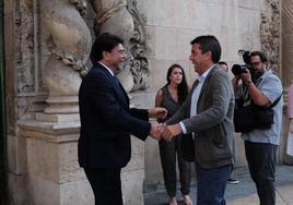 El alcalde de Alicante, Luis Barcala, y el presidente de la Generalitat, Carlos Mazón, se saludan y sonríen en las puertas del ayuntamiento.