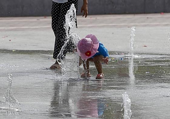 Una niña se refresca en una fuente