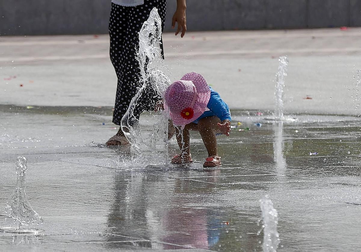 Una niña se refresca en una fuente