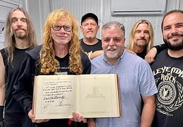Mustaine sostiene el libro de firmas acompañado por el alcalde de Villena.