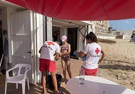 Dos socorristas de la Cruz Roja atendiendo a una niña por una picadura de medusa