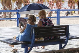 Dos mujeres se protegen del sol con un parasol en Alicante.
