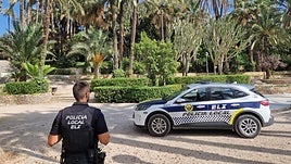 Agente de la Policía Local de Elche junto a un coche patrulla.
