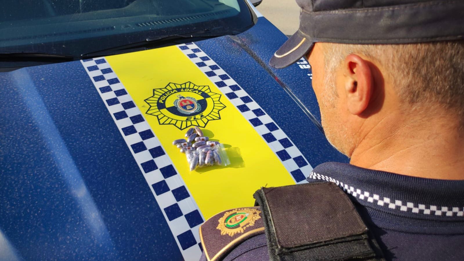 Un agente de la Policía Local de Elche con las 20 bellotas de hachís intervenidas.