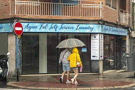 Dos personas pasean un día lluvioso en Alicante.