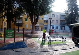 Un trabajador de la limpieza baldea un parque infantil en Villena.