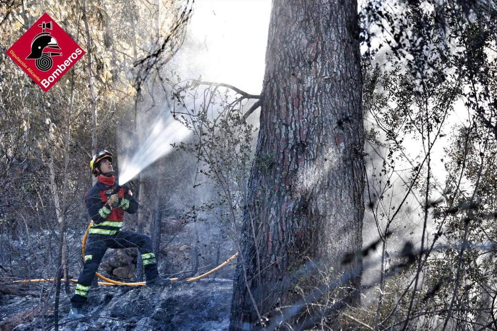 Uno de los bomberos del consorcio refresca la zona quemada en la Marina Alta.