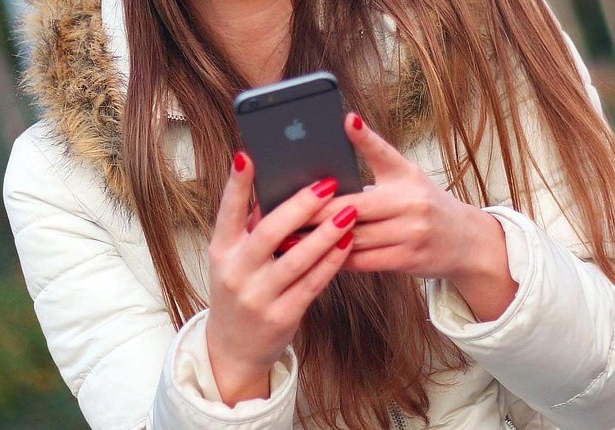 Una adolescente haciendo uso de un teléfono móvil.