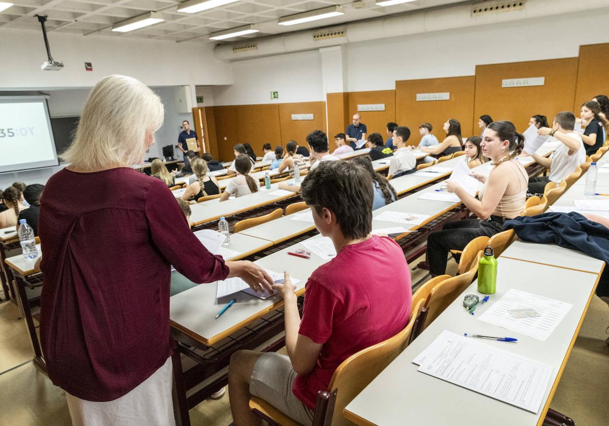 Una docente reparte exámenes en una aula de Alicante.