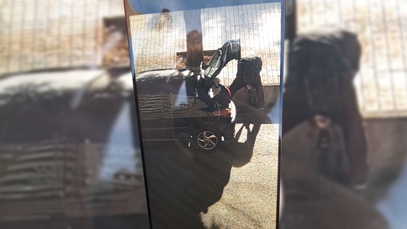 El presunto ladrón haciéndose con una de las rejillas de alcantarilla.