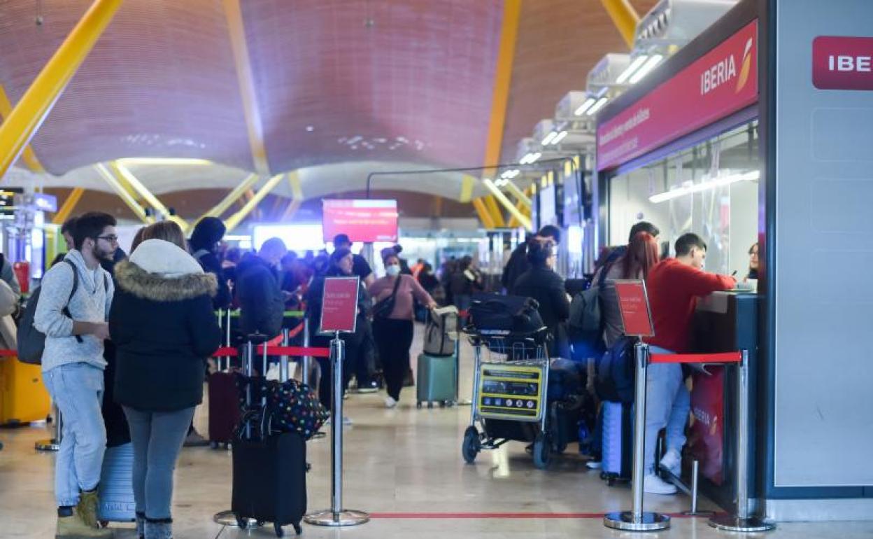Varias personas esperan para embarcar y facturar en la zona de salidas de un aeropuerto.