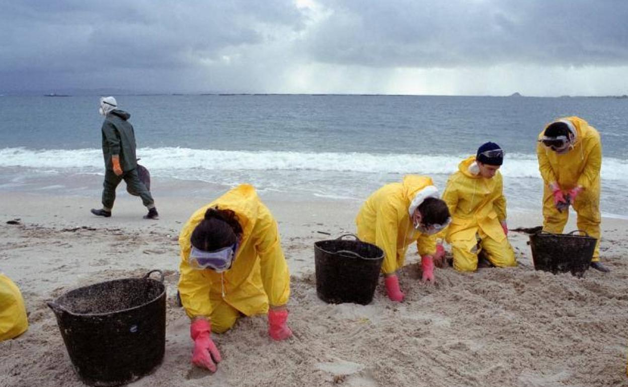 Voluntarios limpian la arena de restos de fuel en la playa de Aviño, en el municipio gallego de Malpica de Bergantiños, después de que la marea arrastrara el chapapote hacia la costa.