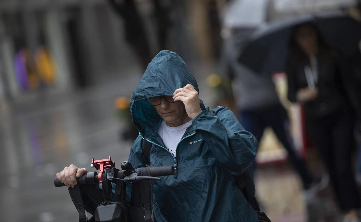 Una mujer se coloca la capucha en una jornada con lluvias 