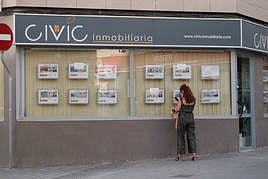 Una mujer mira pisos en alquiler en una inmobiliaria de Alicante.