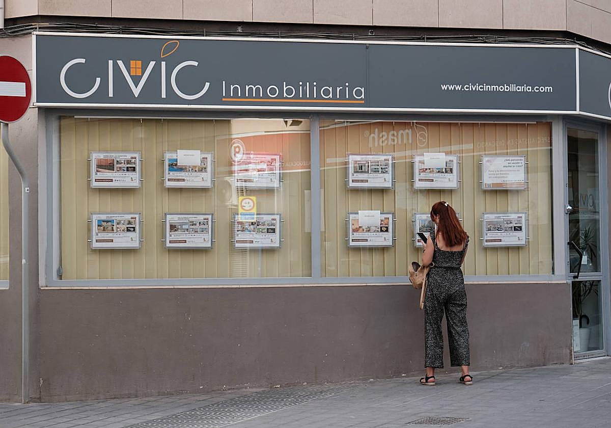 Una mujer mira pisos en alquiler en una inmobiliaria de Alicante.