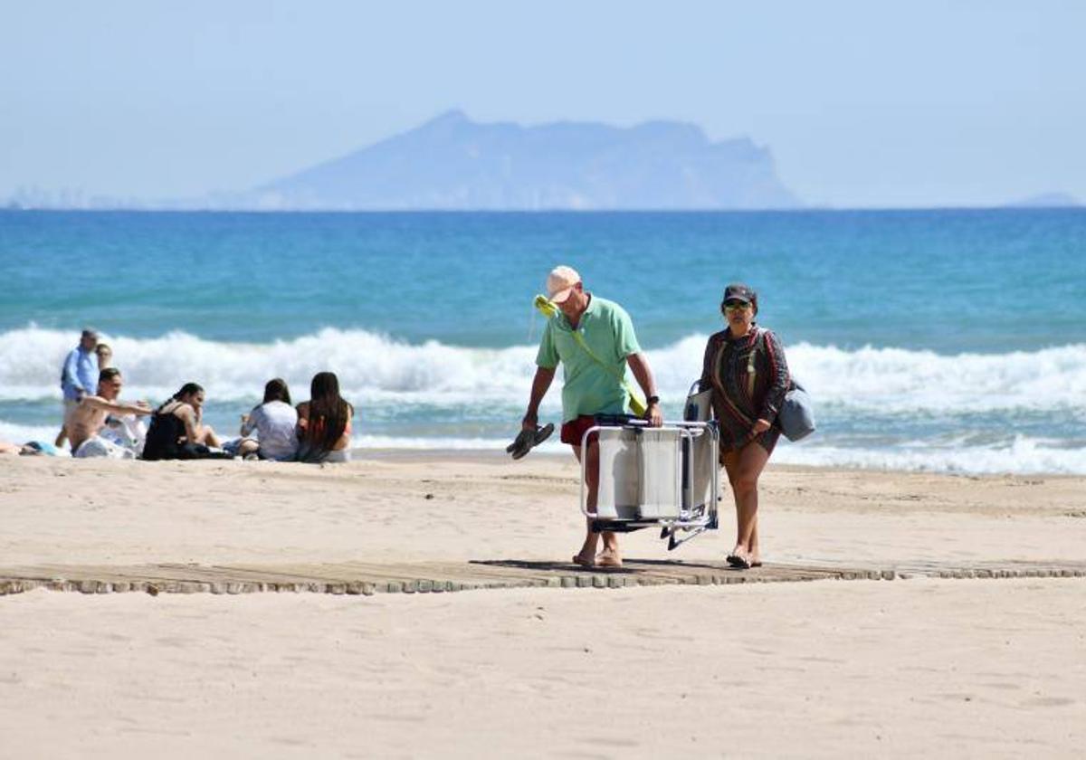 Unas personas se retiran después de pasar la mañana en la playa.