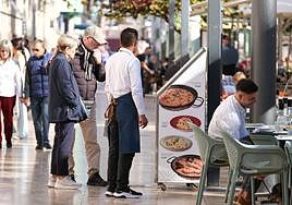 Unos turistas miran el menú de un restaurante de la Explanada.