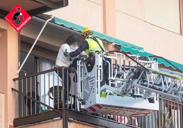 Los bomberos ayudan a una mujer a salir de su vivienda a través del balcón.