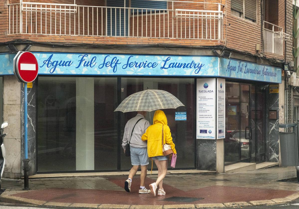 Dos personas se refugian de la lluvia bajo un paraguas.