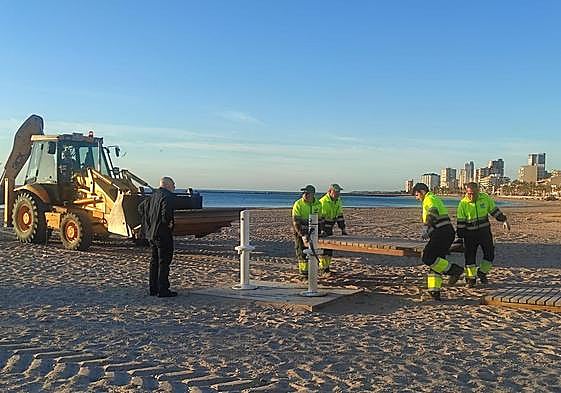 Los operarios, instalando las pasarelas de madera.