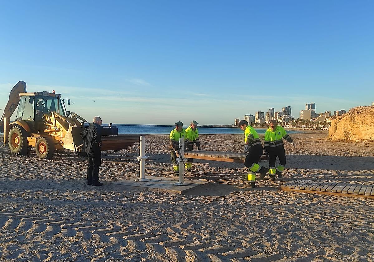 Los operarios, instalando las pasarelas de madera.