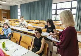 Docente repartiendo exámenes de Selectividad en una aula de Alicante.