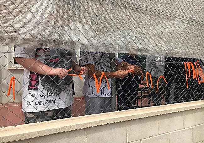 Los alumnos atan lazos naranja en la verja del centro a modo de protesta.
